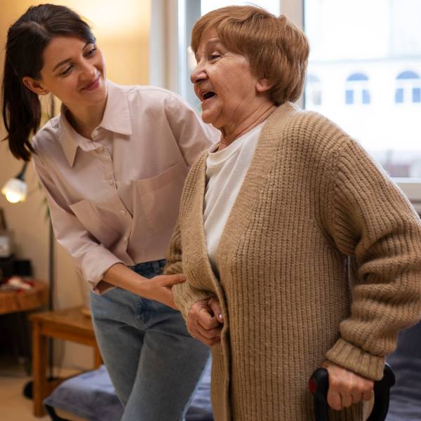 SIL support caregiver helping elderly stand safely at home