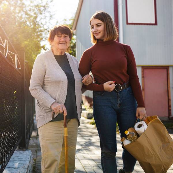 SIL providers assisting senior with groceries and daily walk